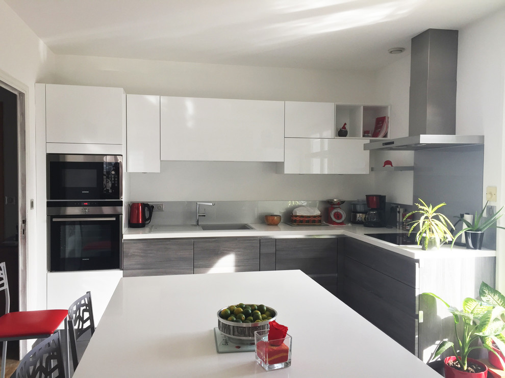 This is an example of a mid-sized modern l-shaped eat-in kitchen in Lyon with flat-panel cabinets, white cabinets, grey splashback, stainless steel appliances and no island.