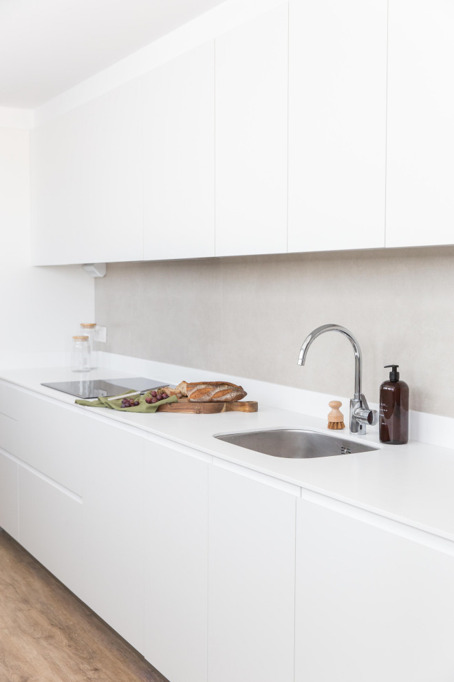 This is an example of a mid-sized scandinavian single-wall separate kitchen in Other with an integrated sink, flat-panel cabinets, white cabinets, marble benchtops, metallic splashback, cement tile splashback, stainless steel appliances, dark hardwood floors, no island, brown floor and white benchtop.