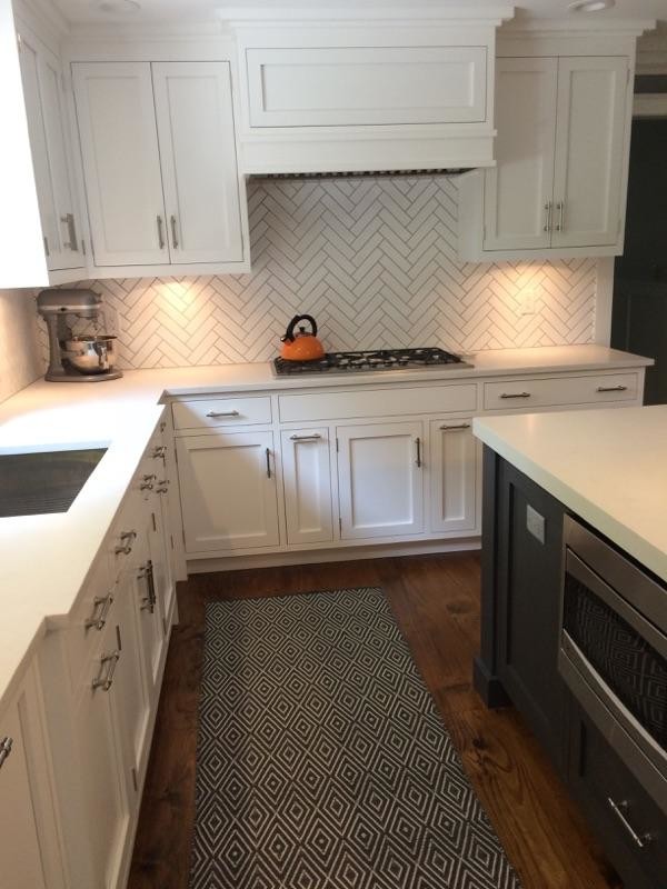 Open concept kitchen - mid-sized transitional l-shaped dark wood floor and brown floor open concept kitchen idea in New York with an undermount sink, shaker cabinets, white cabinets, limestone countertops, white backsplash, porcelain backsplash, stainless steel appliances and an island