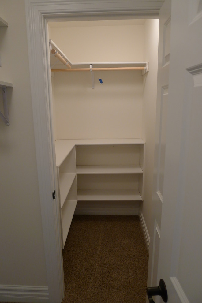 Photo of a small traditional gender-neutral walk-in wardrobe in Milwaukee with open cabinets, white cabinets and carpet.
