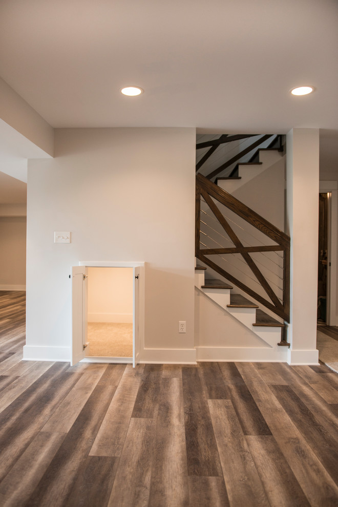 This is an example of a mid-sized country walk-out basement in Kansas City with medium hardwood floors.