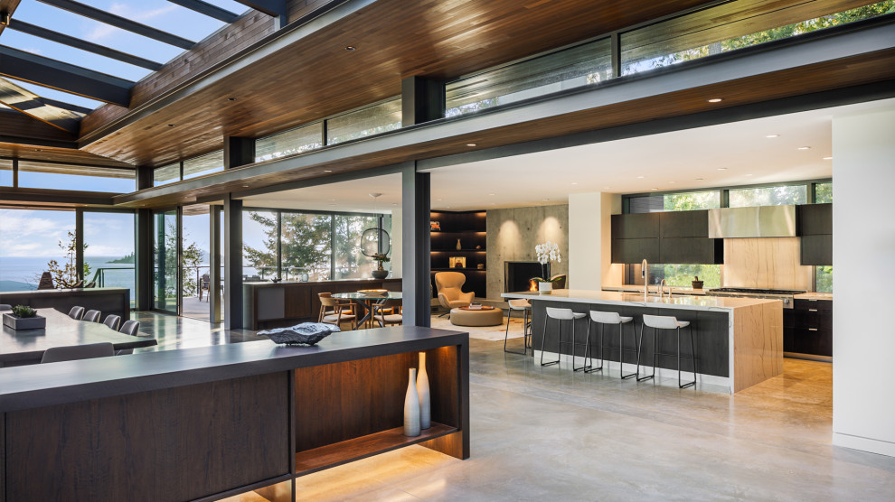 Inspiration for an expansive contemporary l-shaped open plan kitchen in Vancouver with flat-panel cabinets, dark wood cabinets, granite benchtops, window splashback, panelled appliances and with island.