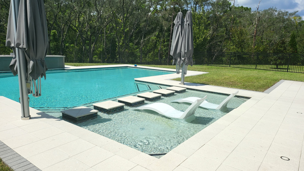 Large modern backyard custom-shaped lap pool in Orlando with concrete pavers.