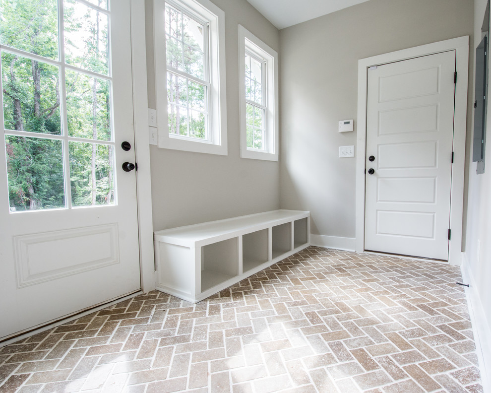 Design ideas for a mid-sized country mudroom in Atlanta with grey walls, brick floors and brown floor.