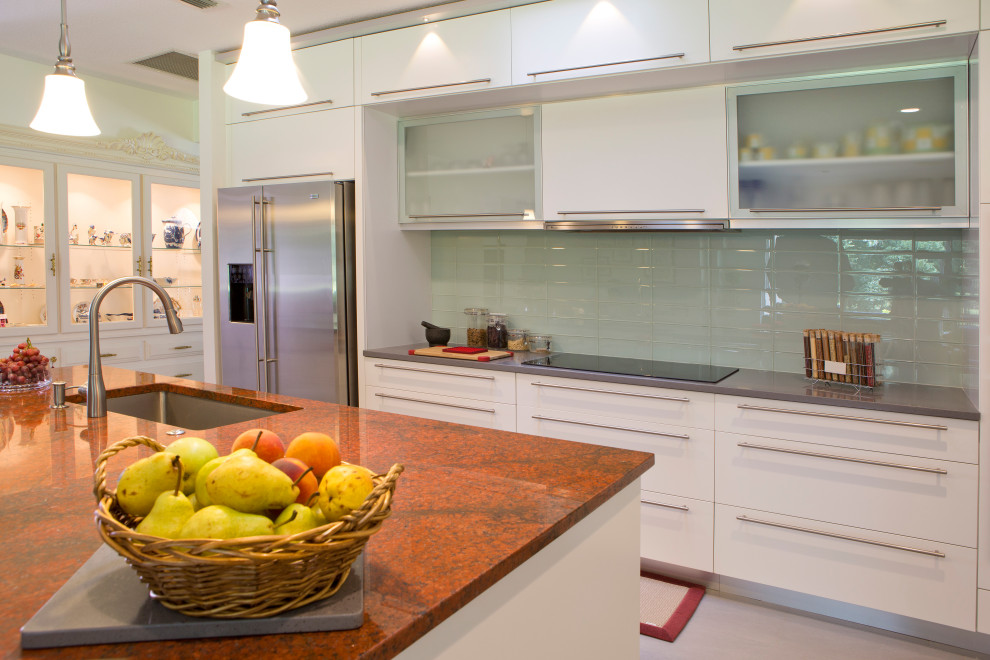 This is an example of a mid-sized contemporary l-shaped open plan kitchen in Orlando with flat-panel cabinets, white cabinets, granite benchtops, with island and red benchtop.