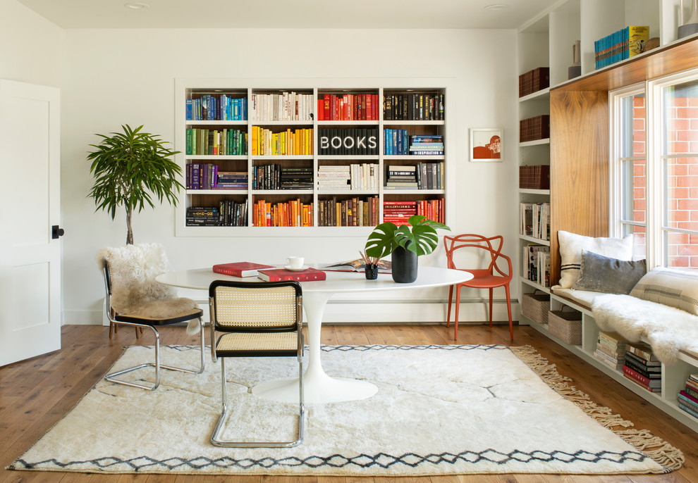 Scandinavian home office in Denver with a library, white walls, medium hardwood floors, a freestanding desk and brown floor.