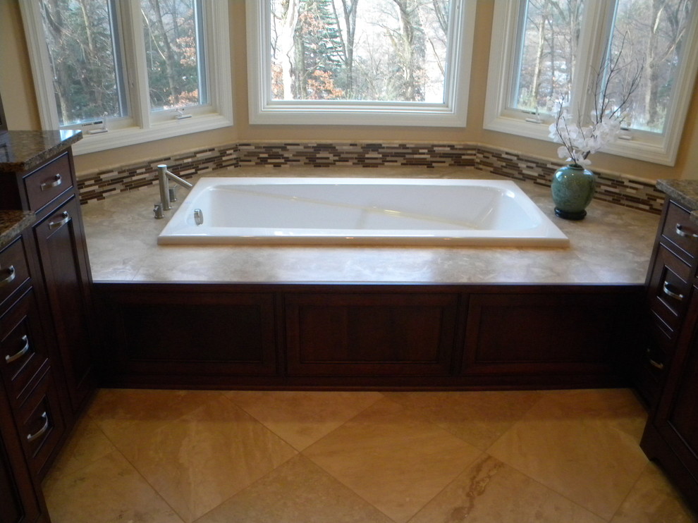Inspiration for a large transitional master beige tile porcelain tile drop-in bathtub remodel with an undermount sink, recessed-panel cabinets, dark wood cabinets, granite countertops, a two-piece toilet and beige walls