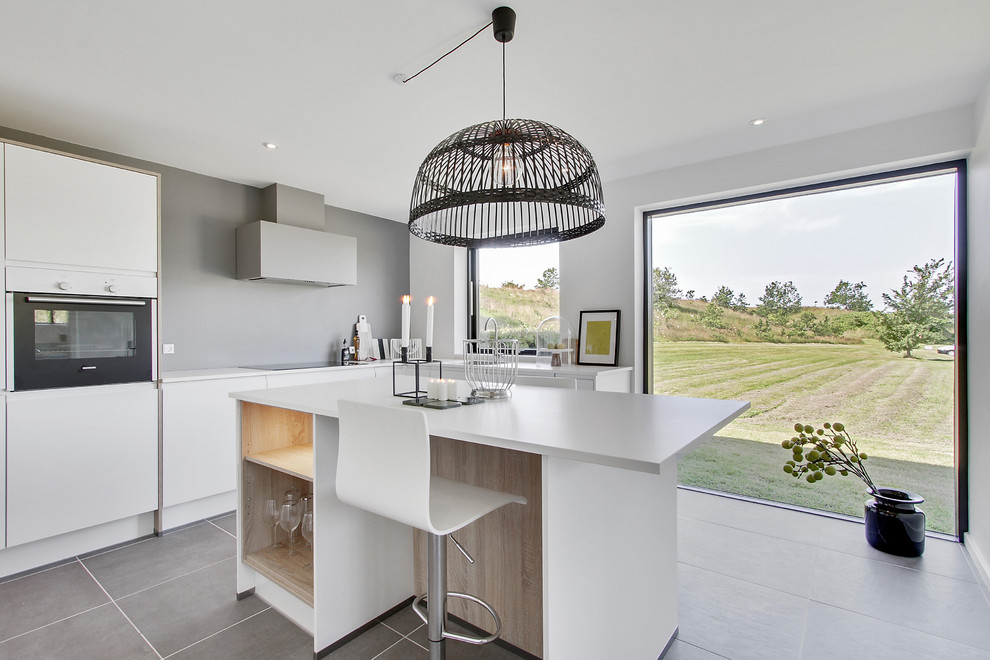 This is an example of a mid-sized contemporary l-shaped open plan kitchen in Aalborg with flat-panel cabinets, white cabinets, white appliances, with island, laminate benchtops and ceramic floors.