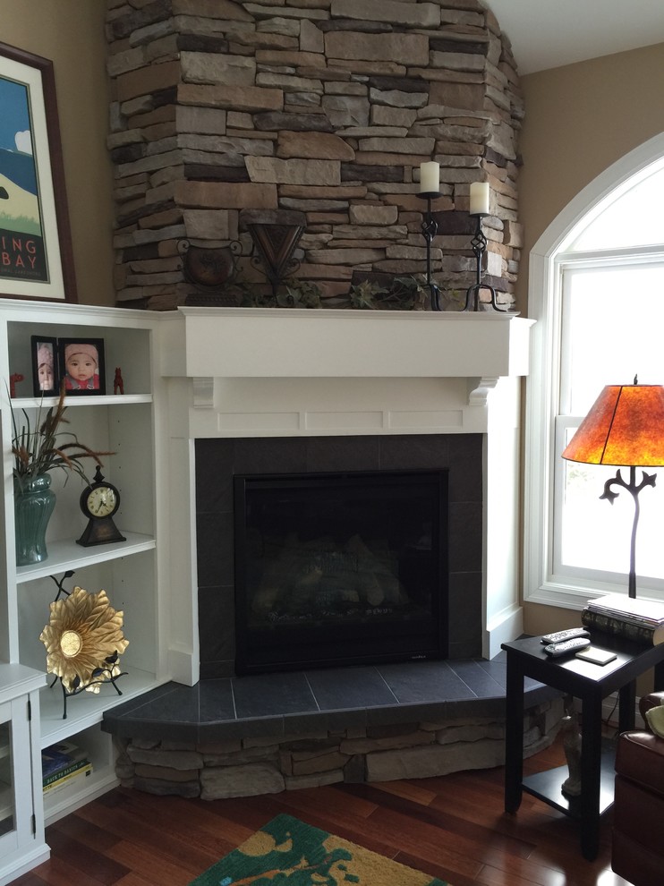 This is an example of a large arts and crafts open concept living room in Other with beige walls, medium hardwood floors, a corner fireplace, a stone fireplace surround and a built-in media wall.