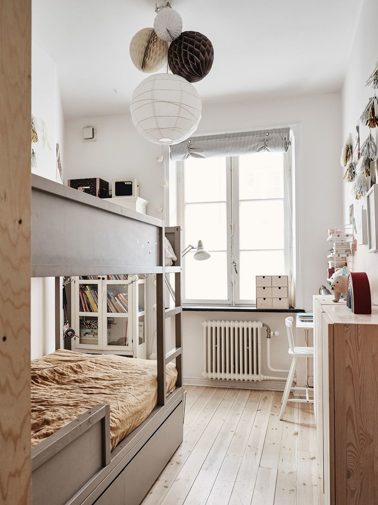 Design ideas for a small scandinavian gender-neutral kids' bedroom for kids 4-10 years old in Malmo with white walls, light hardwood floors and beige floor.