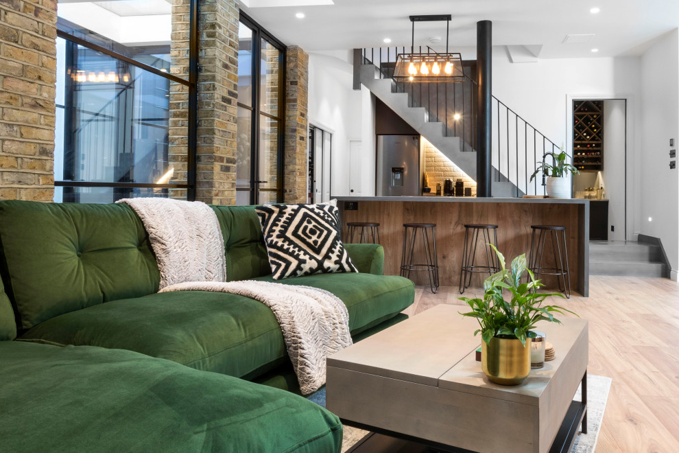 Design ideas for a medium sized industrial look-out basement in London with a home bar, white walls, painted wood flooring, beige floors, a vaulted ceiling and brick walls.