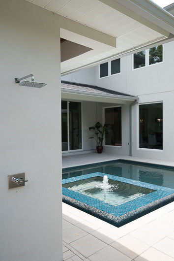 Photo of a modern backyard custom-shaped pool in Orlando with a water feature and concrete pavers.
