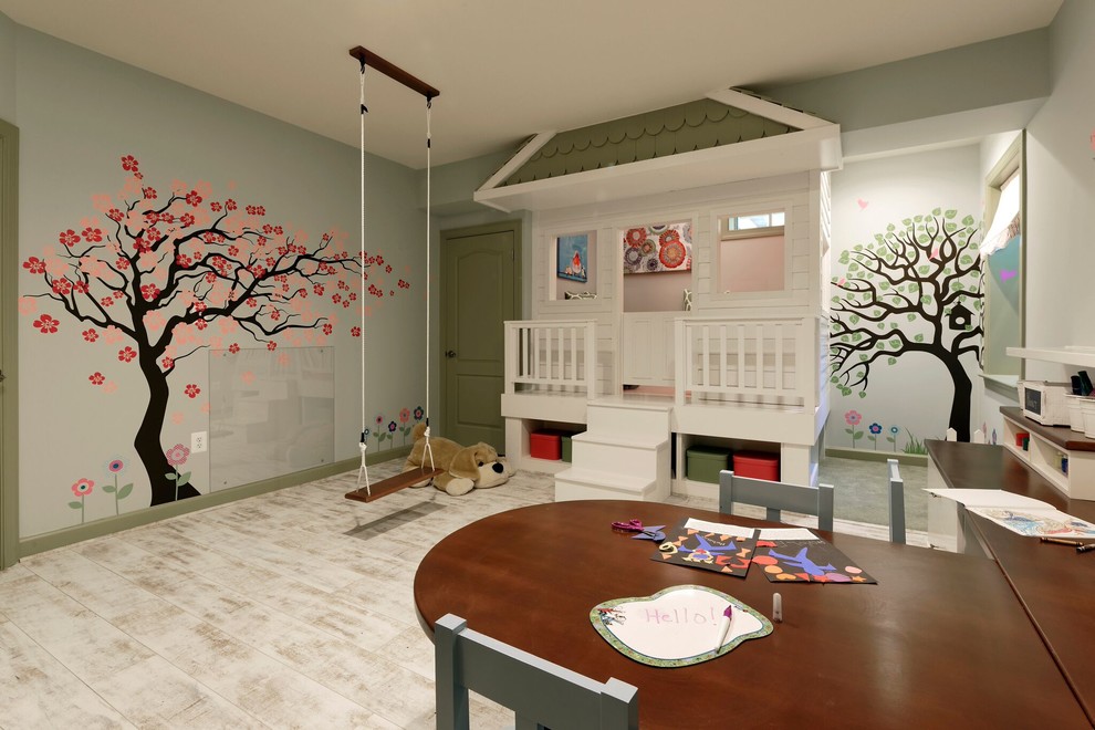 Creative and Unique Playroom - A perfect playroom space for two young girls to grow into.  The space contains a custom made playhouse, complete with hidden trap door, custom built in benches with plenty of toy storage and bench cushions for reading, lounging or play pretend.  In order to mimic an outdoor space, we added an indoor swing.  The side of the playhouse has a small soft area with green carpeting to mimic grass, and a small picket fence.  The tree wall stickers add to the theme.  A huge highlight to the space is the custom designed, custom built craft table with plenty of storage for all kinds of craft supplies.  The rustic laminate wood flooring adds to the cottage theme.
Bob Narod Photography