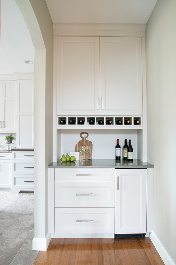 Example of a transitional porcelain tile and beige floor kitchen design with an undermount sink, beige backsplash, black appliances and an island