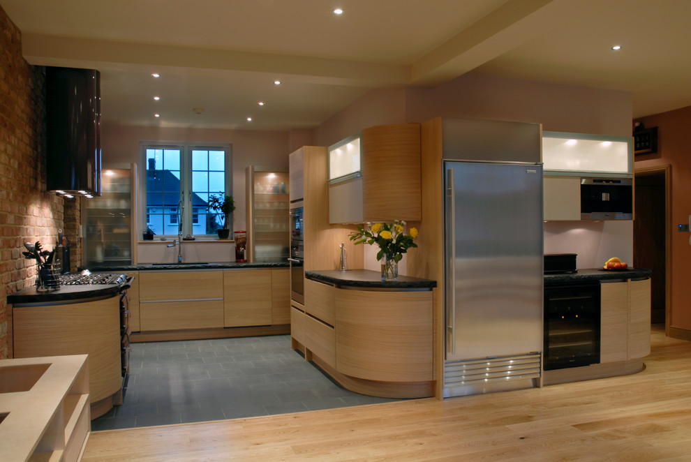 Design ideas for a mid-sized modern u-shaped open plan kitchen in Hertfordshire with a drop-in sink, flat-panel cabinets, light wood cabinets, granite benchtops, red splashback, brick splashback, stainless steel appliances, light hardwood floors and no island.