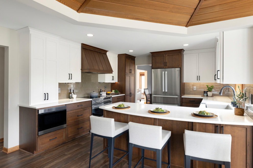 This is an example of a large contemporary u-shaped kitchen/diner in Minneapolis with a single-bowl sink, recessed-panel cabinets, medium wood cabinets, quartz worktops, beige splashback, glass tiled splashback, stainless steel appliances, vinyl flooring, a breakfast bar, brown floors, white worktops and a wood ceiling.
