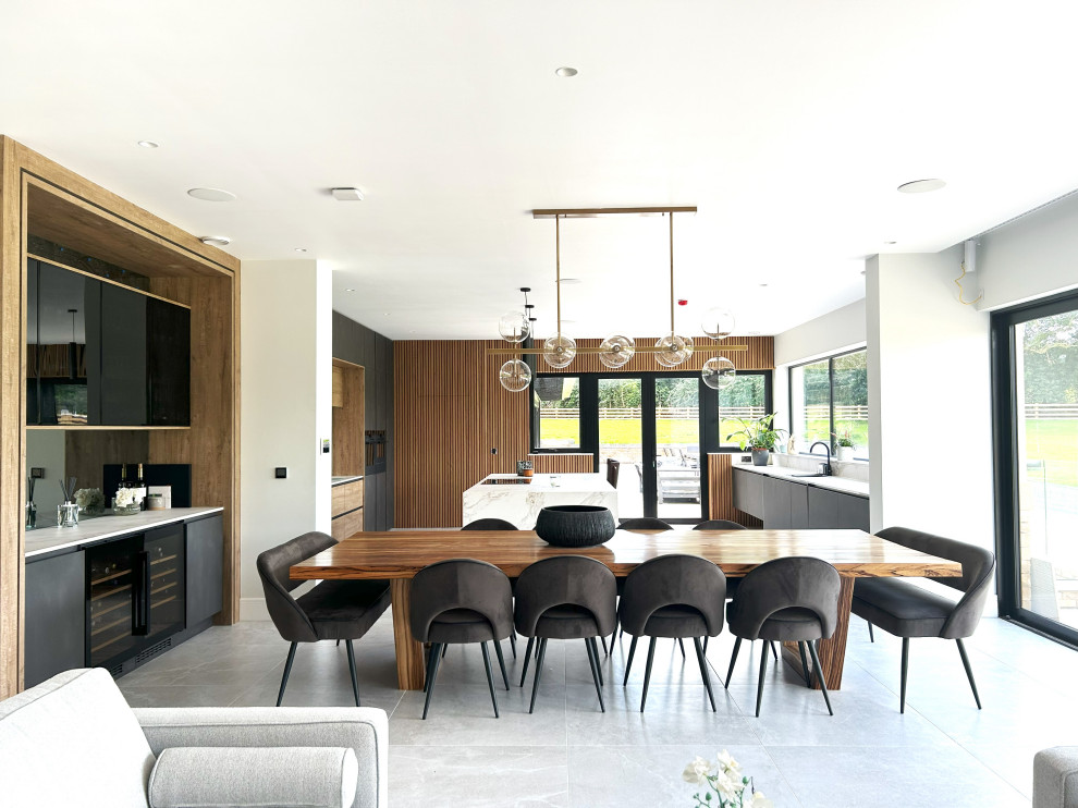 Стильный дизайн: большая кухня: освещение в современном стиле с плоскими фасадами, черной техникой и островом - последний тренд
