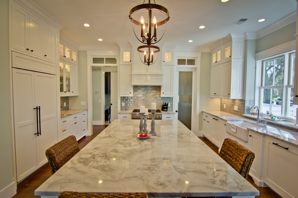 This is an example of a mid-sized traditional u-shaped kitchen pantry in Atlanta with a farmhouse sink, flat-panel cabinets, white cabinets, marble benchtops, grey splashback, stainless steel appliances, medium hardwood floors and with island.