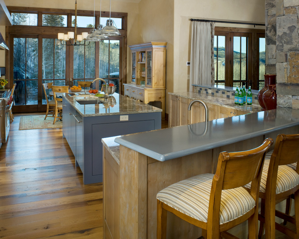 Large mountain style galley medium tone wood floor eat-in kitchen photo in Denver with an undermount sink, recessed-panel cabinets, light wood cabinets, granite countertops, multicolored backsplash, mosaic tile backsplash, stainless steel appliances and an island