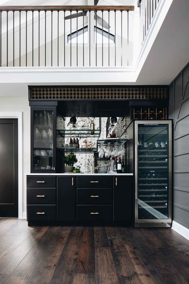 Inspiration for a mid-sized transitional single-wall home bar in Chicago with flat-panel cabinets, black cabinets, quartz benchtops, multi-coloured splashback, mirror splashback, medium hardwood floors, brown floor and white benchtop.