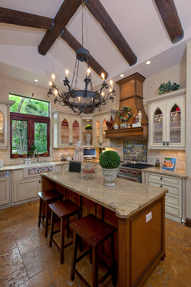 Example of a large mountain style u-shaped slate floor and brown floor enclosed kitchen design in Miami with a farmhouse sink, recessed-panel cabinets, beige cabinets, granite countertops, beige backsplash, stone tile backsplash, stainless steel appliances and an island