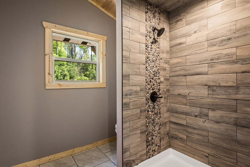 Mid-sized mountain style master ceramic tile and white floor doorless shower photo with recessed-panel cabinets, brown cabinets, a two-piece toilet, brown walls, an undermount sink, granite countertops and multicolored countertops