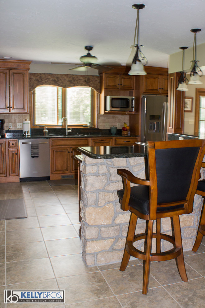 Inspiration for a large country l-shaped eat-in kitchen remodel in Cincinnati with raised-panel cabinets, medium tone wood cabinets, granite countertops, beige backsplash, stone tile backsplash, stainless steel appliances and an island