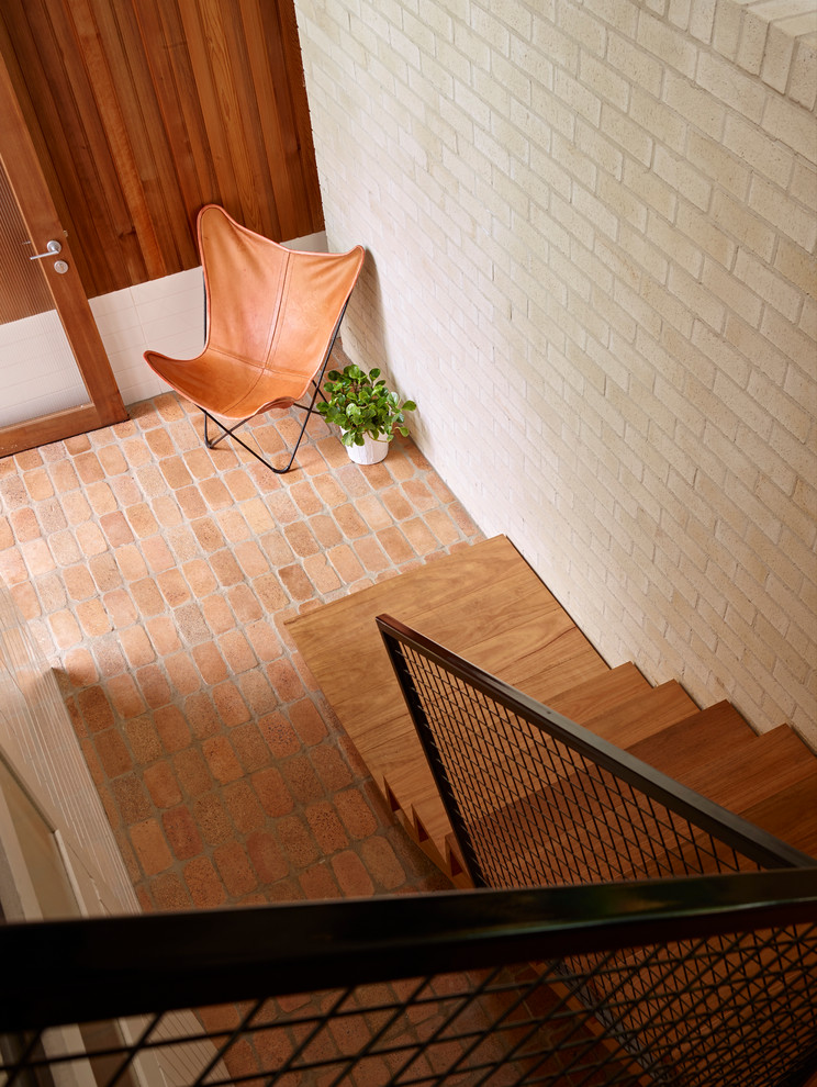 Design ideas for a large modern foyer in Brisbane with brick floors, a single front door and a glass front door.