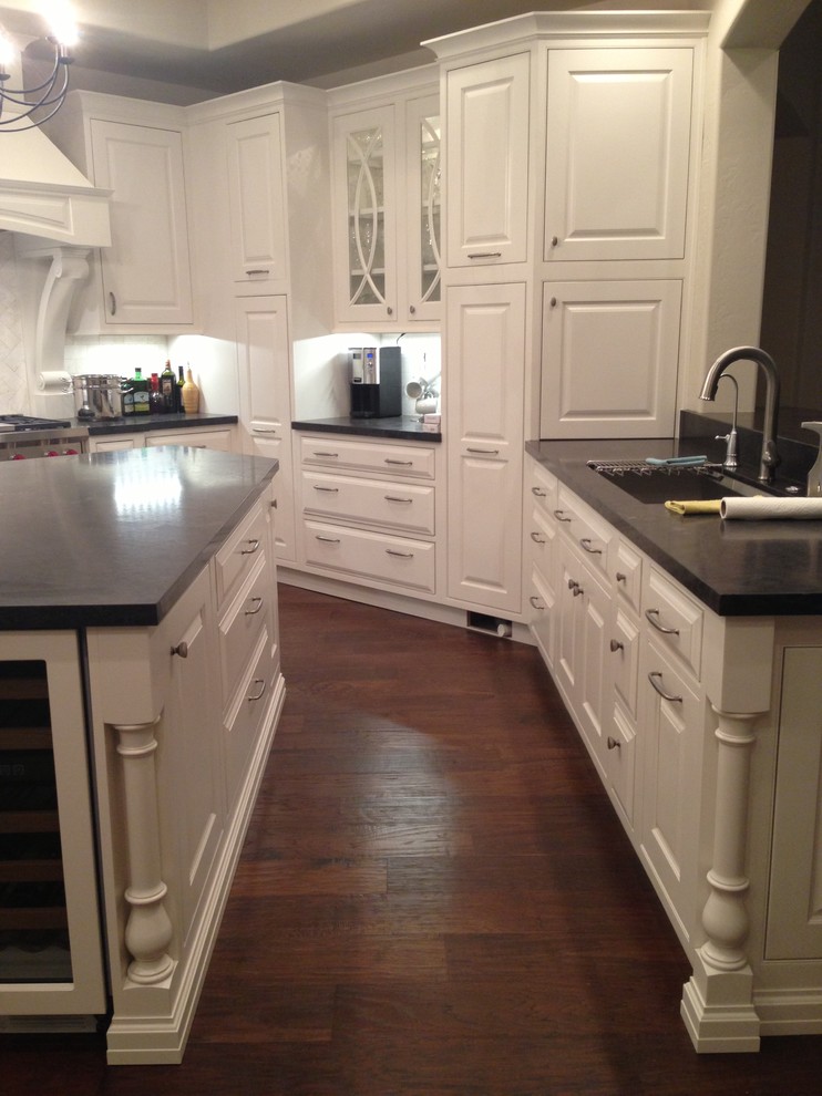 Transitional dark wood floor kitchen photo in Phoenix with white cabinets, granite countertops, white backsplash, stainless steel appliances and an island