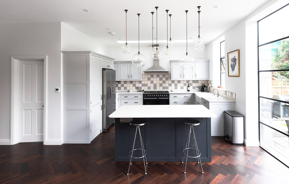Design ideas for a mid-sized transitional open plan kitchen in London with a farmhouse sink, shaker cabinets, grey cabinets, quartzite benchtops, ceramic splashback, stainless steel appliances, dark hardwood floors and with island.