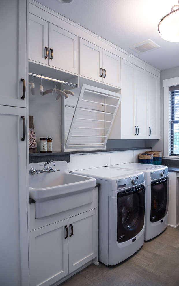 Design ideas for a transitional l-shaped dedicated laundry room in Portland with shaker cabinets, white cabinets, grey walls, a side-by-side washer and dryer, grey floor, grey benchtop and a drop-in sink.