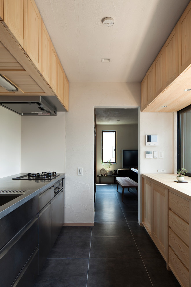 Mid-sized asian single-wall separate kitchen in Tokyo with an integrated sink, recessed-panel cabinets, light wood cabinets, stainless steel benchtops, a peninsula and grey floor.