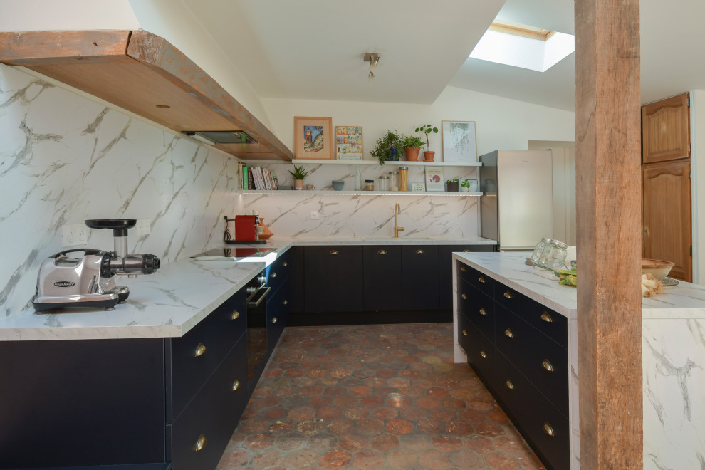 This is an example of a large transitional l-shaped open plan kitchen in Paris with an undermount sink, beaded inset cabinets, blue cabinets, laminate benchtops, white splashback, marble splashback, panelled appliances, terra-cotta floors, with island, orange floor and white benchtop.