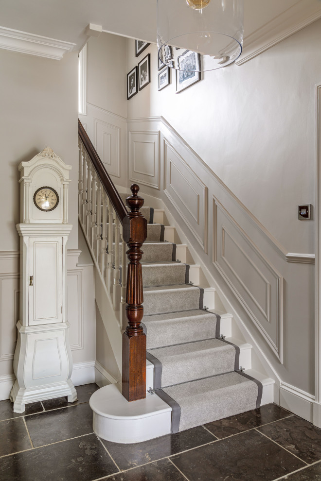 Mid-sized traditional carpeted u-shaped staircase in Essex with carpet risers, wood railing and decorative wall panelling.