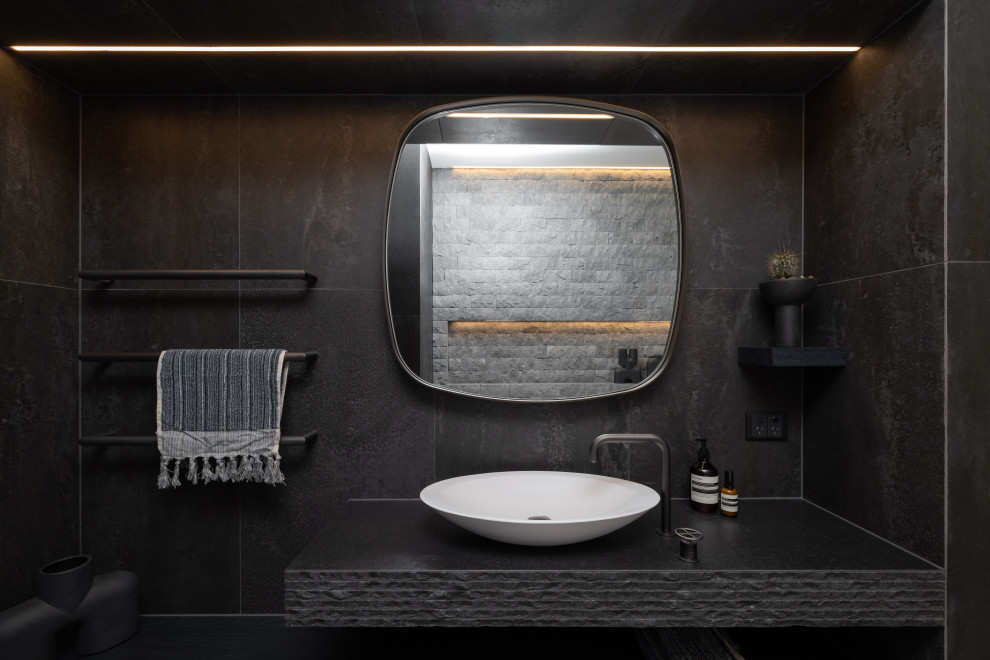 Idée de décoration pour une salle de bain urbaine de taille moyenne avec un placard à porte plane, des portes de placard bleues, une baignoire indépendante, WC à poser, un carrelage gris, du carrelage en pierre calcaire, un mur marron, un sol en carrelage de porcelaine, une vasque, un plan de toilette en granite, un sol gris, une cabine de douche à porte battante, un plan de toilette noir, une niche, meuble simple vasque, meuble-lavabo encastré et boiseries.