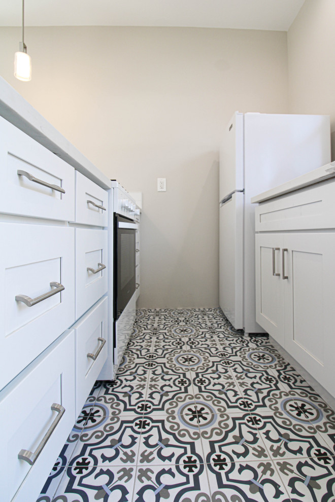 This is an example of a small galley eat-in kitchen in Los Angeles with a drop-in sink, recessed-panel cabinets, white cabinets, quartzite benchtops, multi-coloured splashback, ceramic splashback, white appliances, cement tiles, no island, multi-coloured floor and white benchtop.
