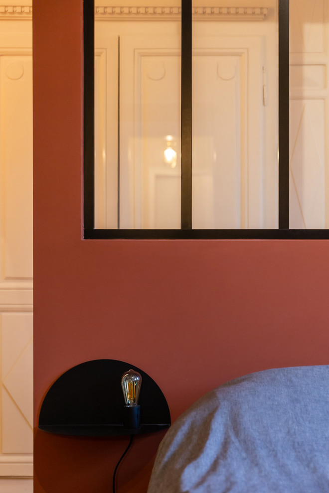 Idée de décoration pour une grande chambre parentale minimaliste avec un mur rouge, un sol en bois brun, aucune cheminée et un sol marron.