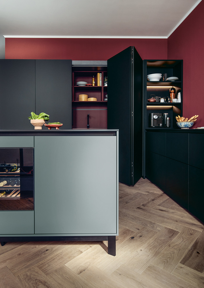 This is an example of a large asian l-shaped open plan kitchen in Nuremberg with flat-panel cabinets, black cabinets, red splashback, black appliances, with island and white benchtop.