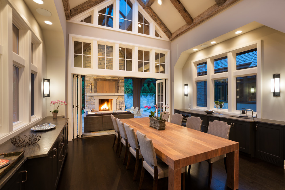 Photo of a transitional kitchen/dining combo in Minneapolis with grey walls, dark hardwood floors, a standard fireplace and a stone fireplace surround.