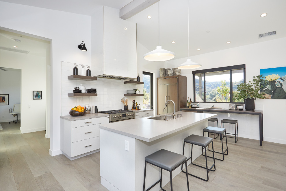 This is an example of a mid-sized contemporary u-shaped eat-in kitchen in Dallas with an undermount sink, flat-panel cabinets, white cabinets, quartz benchtops, white splashback, ceramic splashback, panelled appliances, light hardwood floors, with island, grey floor and grey benchtop.