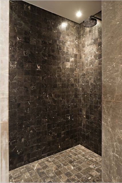 Modern bathroom in New York with a corner shower, brown tile and stone tile.