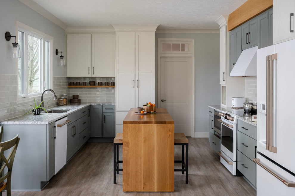 Medium sized modern u-shaped kitchen/diner in Indianapolis with a submerged sink, shaker cabinets, white cabinets, granite worktops, beige splashback, stainless steel appliances, light hardwood flooring and an island.
