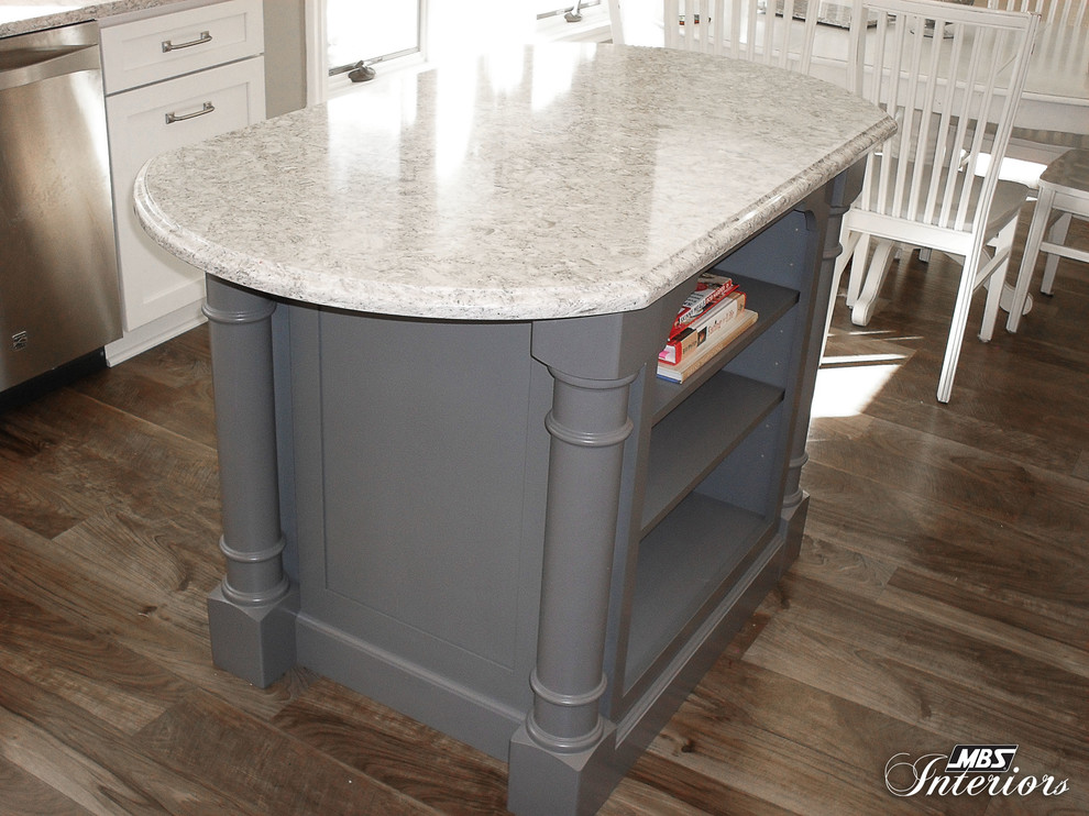 Eat-in kitchen - mid-sized transitional u-shaped medium tone wood floor eat-in kitchen idea with a farmhouse sink, shaker cabinets, white cabinets, quartzite countertops, white backsplash, subway tile backsplash, stainless steel appliances and an island