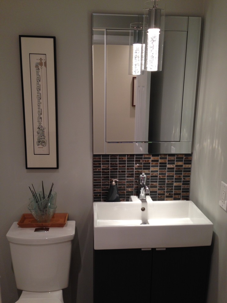 This is an example of a small contemporary powder room in Toronto with an integrated sink, flat-panel cabinets, dark wood cabinets, a two-piece toilet, brown tile, mosaic tile and grey walls.