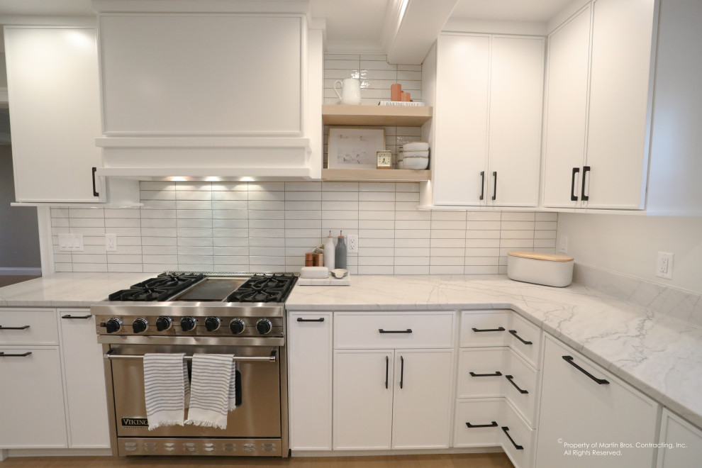 Example of a large transitional u-shaped light wood floor open concept kitchen design with an undermount sink, flat-panel cabinets, white cabinets, quartzite countertops, white backsplash, porcelain backsplash, stainless steel appliances, an island and white countertops