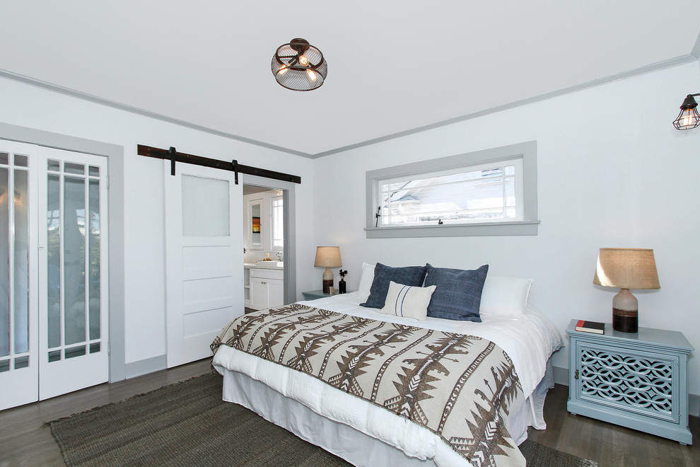 Country bedroom in Los Angeles with white walls, dark hardwood floors and grey floor.