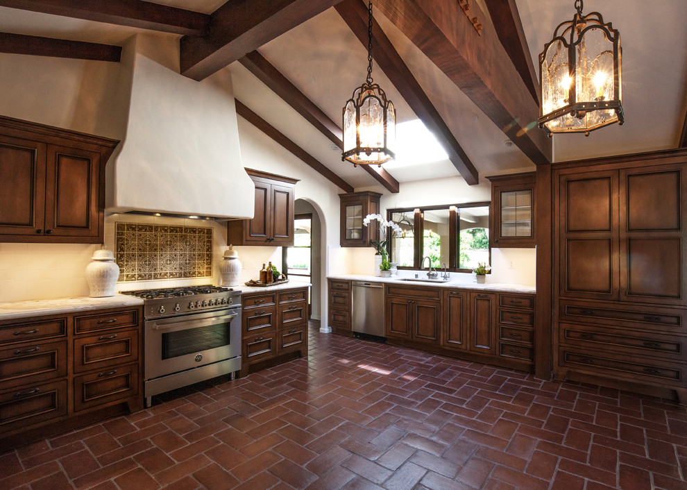 Inspiration for a large mediterranean u-shaped terra-cotta tile eat-in kitchen remodel in Santa Barbara with an undermount sink, recessed-panel cabinets, distressed cabinets, marble countertops, white backsplash, subway tile backsplash, stainless steel appliances and no island