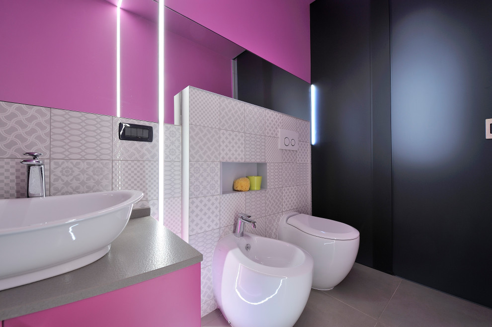 Photo of a small contemporary powder room in Other with a two-piece toilet, pink walls, a vessel sink, grey floor, grey benchtops and a floating vanity.