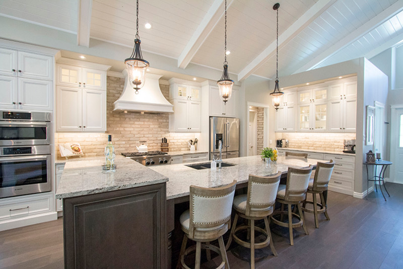 Large transitional l-shaped eat-in kitchen photo with a double-bowl sink, shaker cabinets, white cabinets, beige backsplash, stainless steel appliances and an island