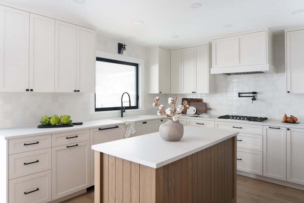 Design ideas for a mid-sized transitional u-shaped eat-in kitchen in Vancouver with a single-bowl sink, shaker cabinets, white cabinets, quartz benchtops, white splashback, porcelain splashback, stainless steel appliances, medium hardwood floors, with island and grey benchtop.